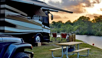 An RV parked along the waterway with a picnic table