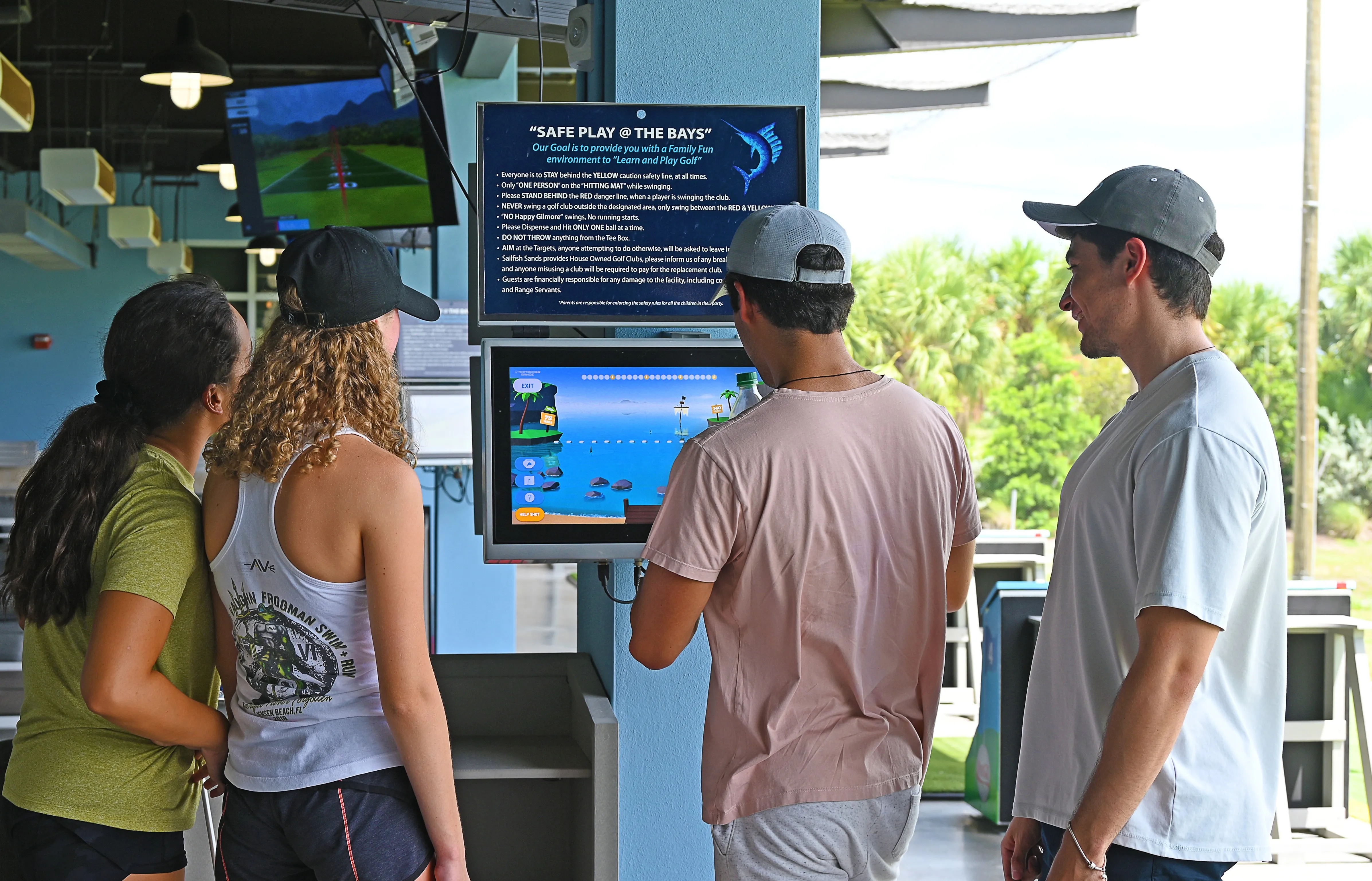 four teens looking at a hitting bay screen