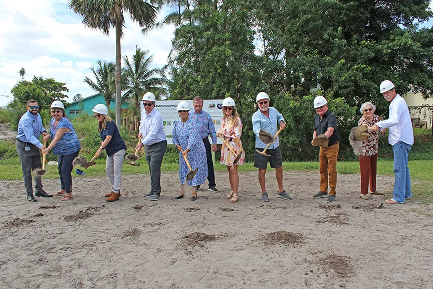 Image of CRA staff, CRA board members, and elected officials shoveling dirt with gold shovels and hard hats during the groundbreaking ceremony of El Camino in the Golden Gate CRA.